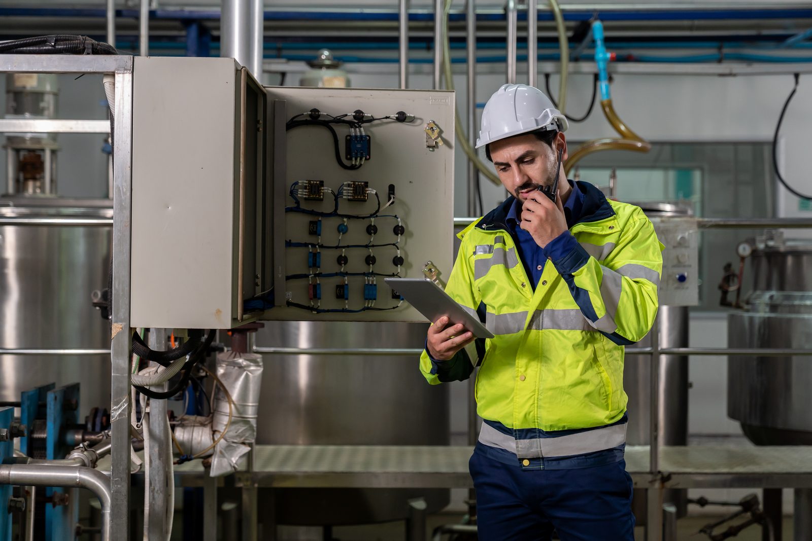 A plant worker studying a tablet while radioing in, representing the 16.7 million American workers in AI-exposed occupations with limited mobility options